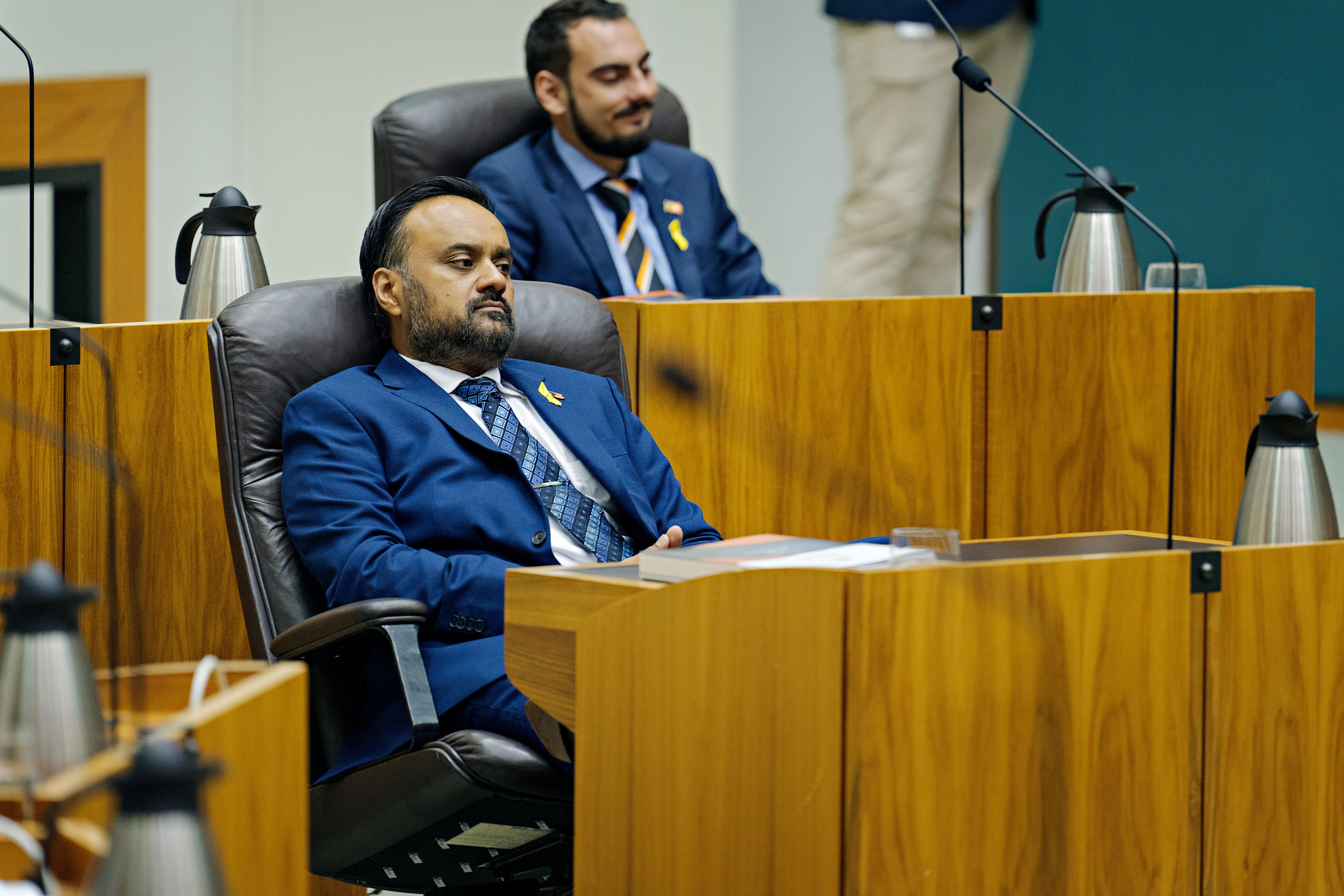 A man leans back in his chair in parliament