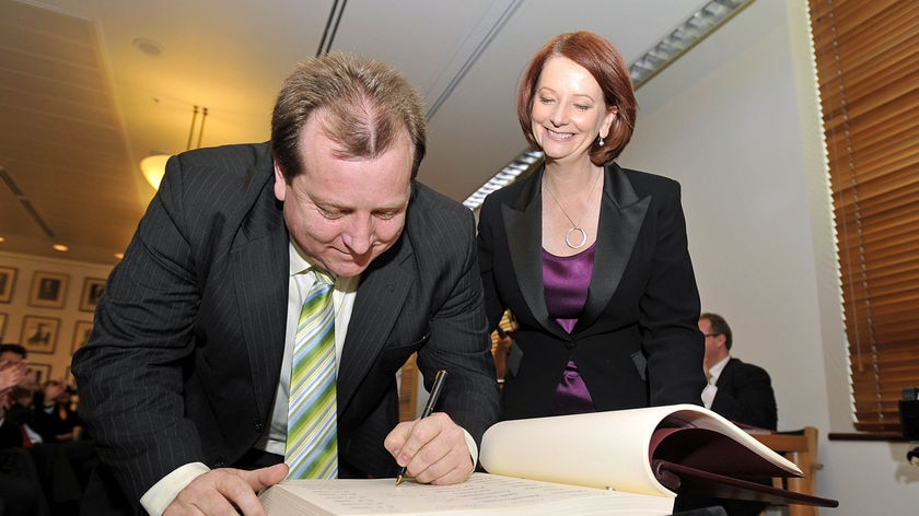 Julia Gillard watches as the new member for McEwen, Rob Mitchell, signs the ALP caucus book.