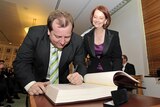 Julia Gillard watches as the new member for McEwen, Rob Mitchell, signs the ALP caucus book.