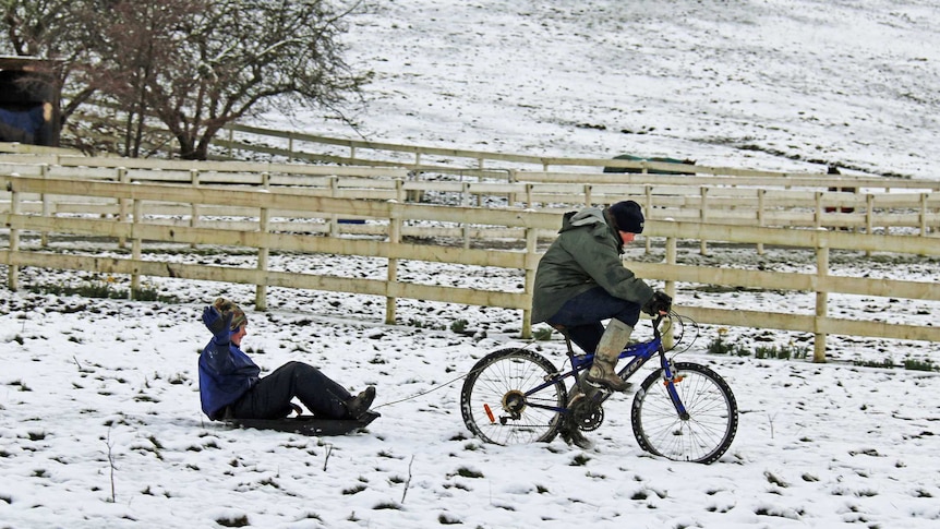 Kids enjoy an improvised sleigh ride on fresh snowfall in Collinsvale, north of Hobart.