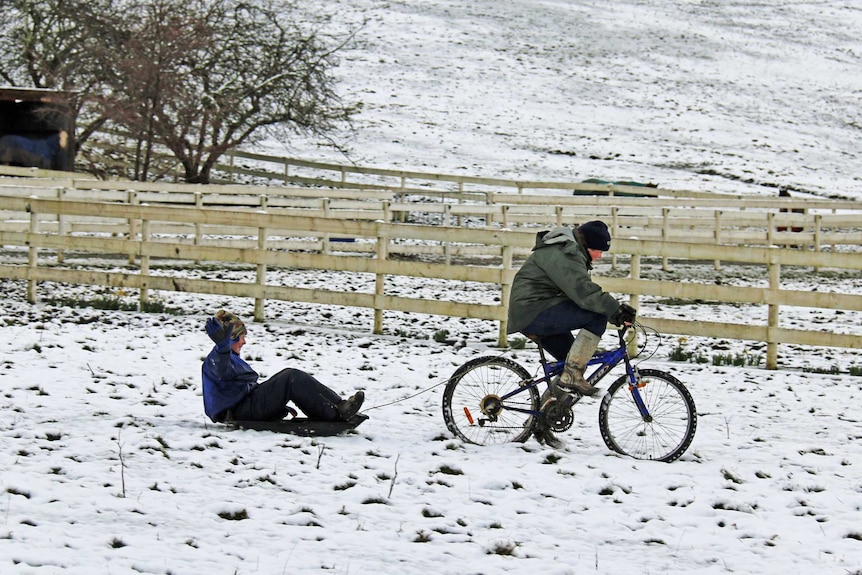 Kids enjoy an improvised sleigh ride on fresh snowfall in Collinsvale, north of Hobart.