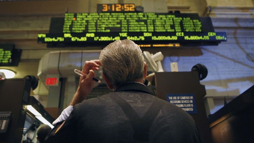 A trader scratches his head as he looks up at the board from the floor at the New York Stock Exchange.