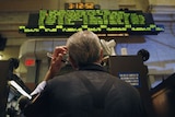 A trader scratches his head as he looks up at the board from the floor at the New York Stock Exchange