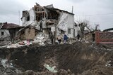 Crater from missile strike seen next to destroyed home.
