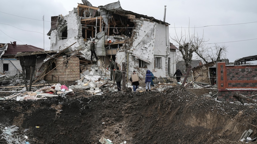 Crater from missile strike seen next to destroyed home.