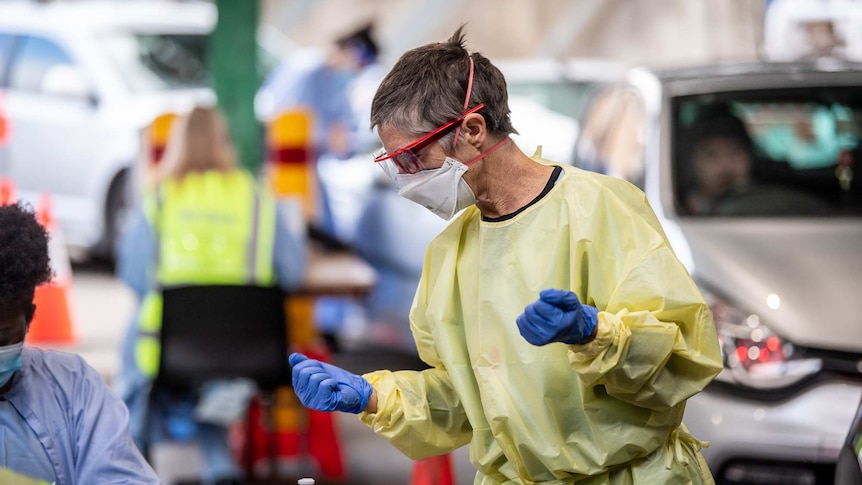 A woman at a testing centre wears full PPE.