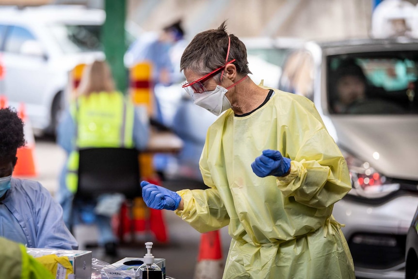 A woman at a testing centre wears full PPE.