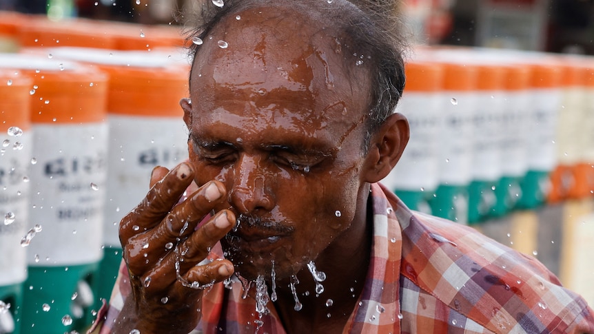 Man sprays water in his face during heatwave May 2023 India 
