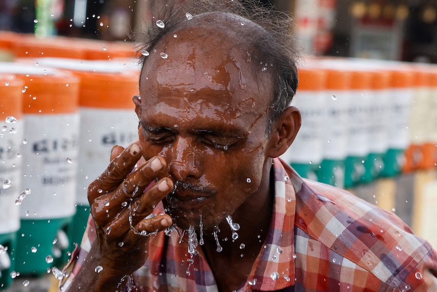Man sprays water in his face during heatwave May 2023 India 