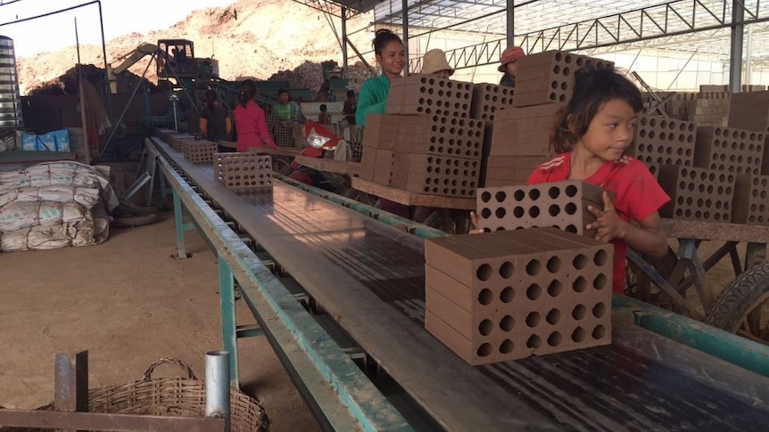 A girl unloading bricks from conveyor belts in Cambodia