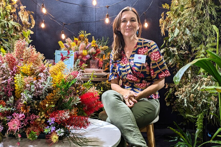 A woman surrounded by hundreds of exotic native flowers of every colour imaginable.