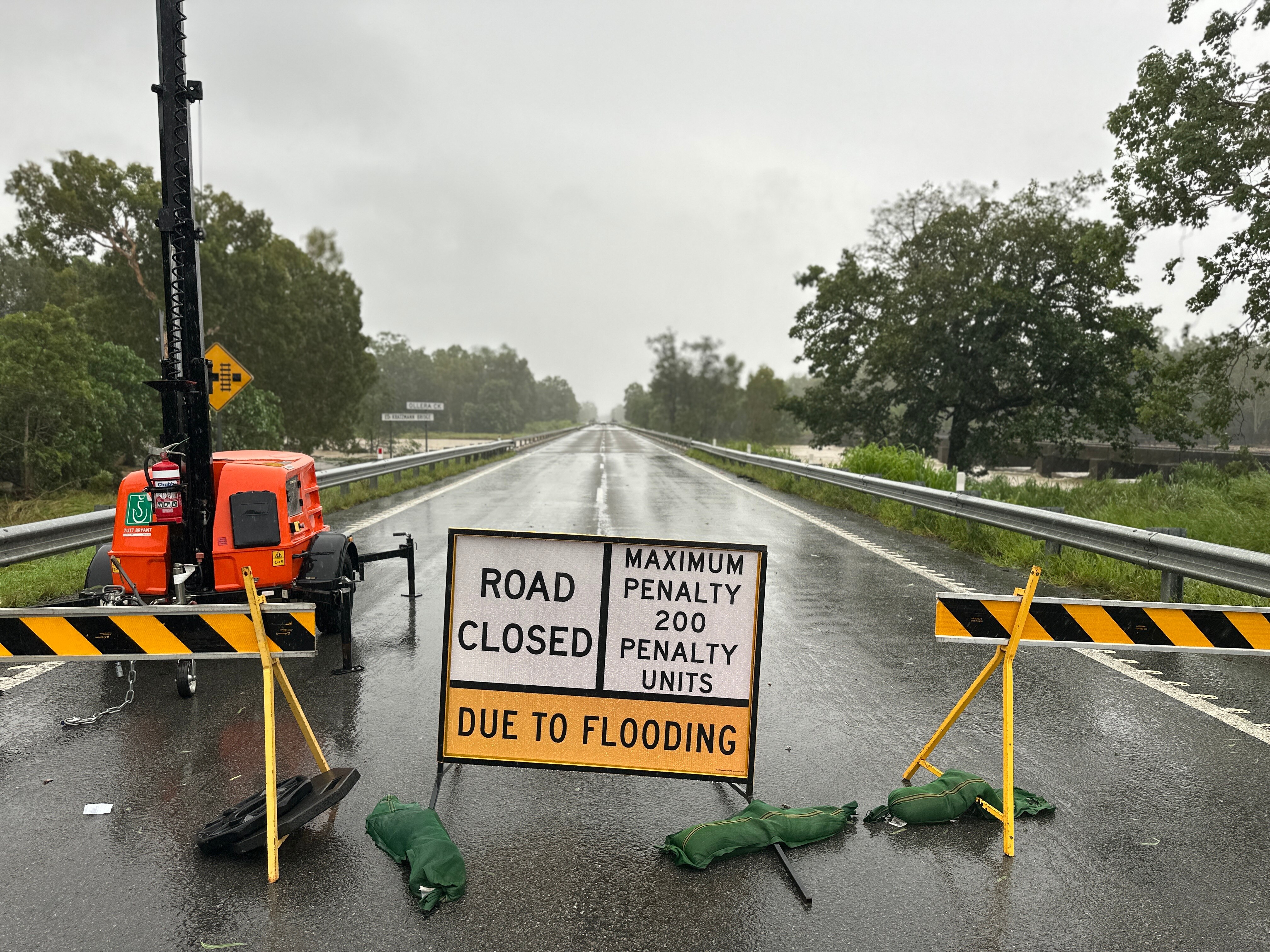 A "road closed" sign on a wet stretch of country highway.