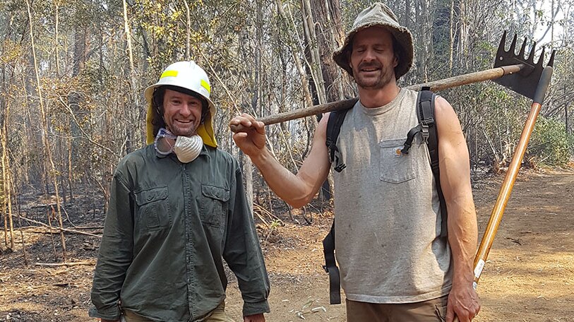 Two men holding fire equipment.
