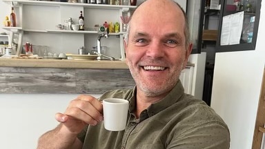 man smiles with espress cup in hand