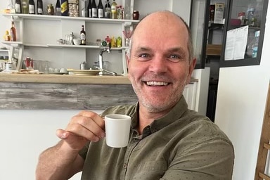 man smiles with espress cup in hand