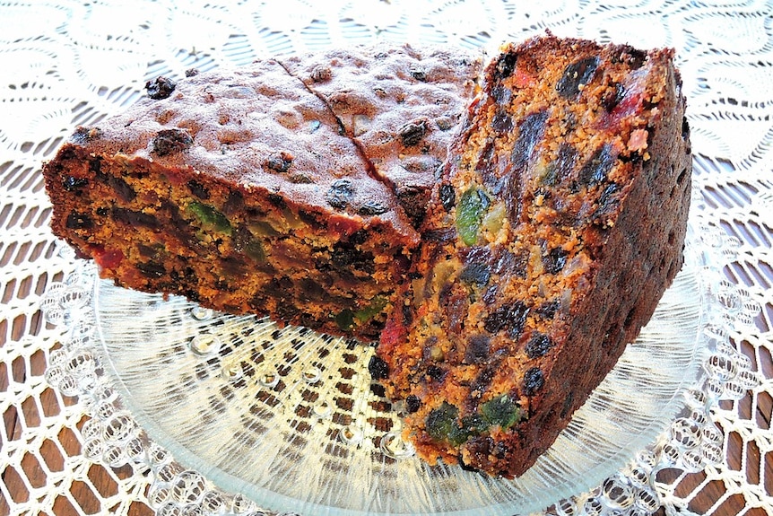 Dark Christmas cake, sliced and placed on a glass plate.