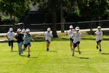 TV still of anonymous primary school children running on school oval at school in Brisbane