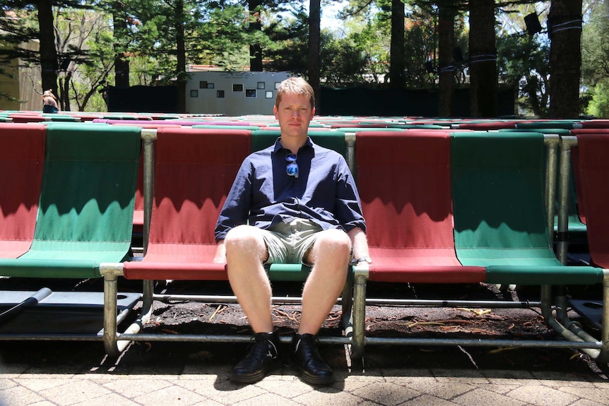 Film program director Tom Vincent sits on a front row deckchair at the Somerville Auditorium, UWA.