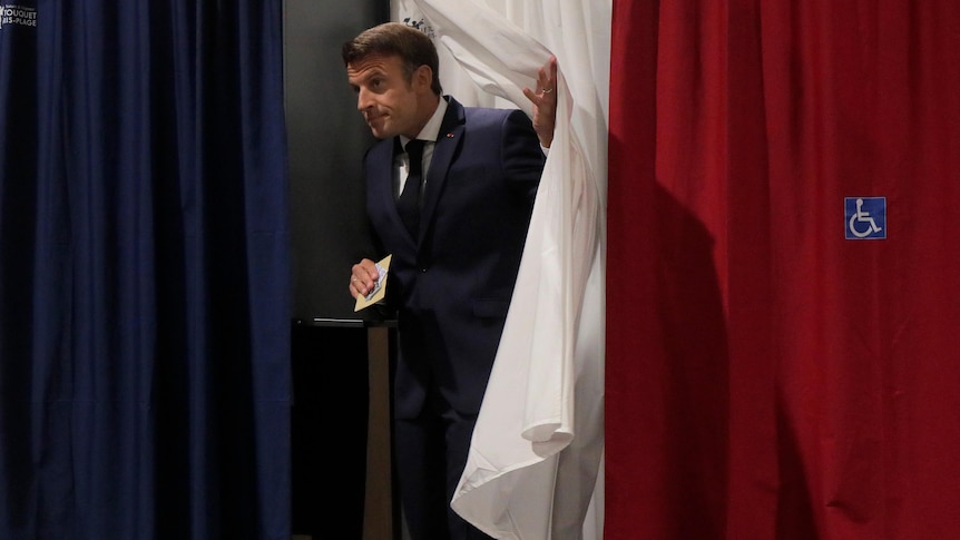 Man leaves voting booth with blue,white and red sheets 