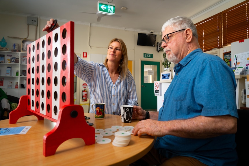 A man with grey hair and a woman with short blonde hair playing a game of connect four. 
