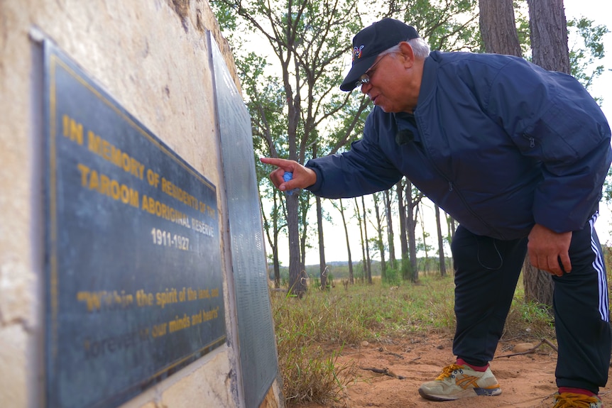 A man leans forward to read a memorial.