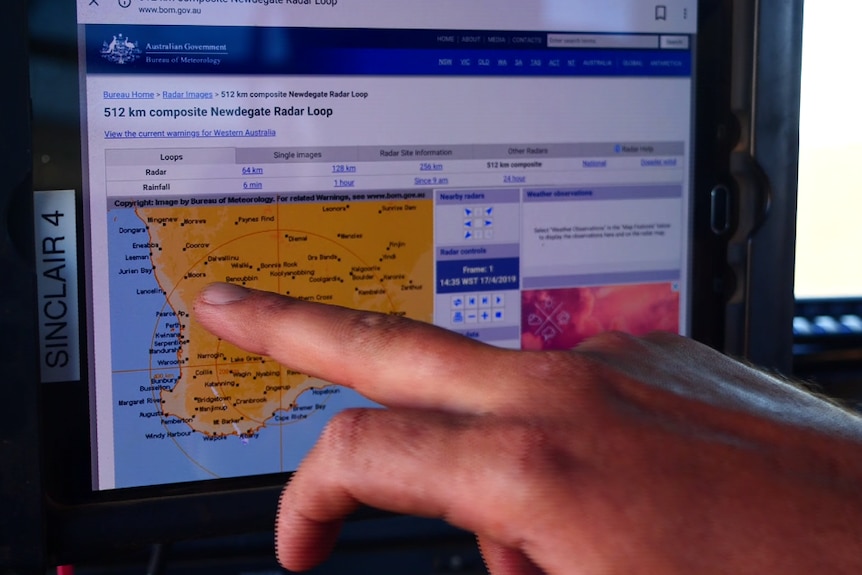 A man pointing his finger at the weather radar on a tablet