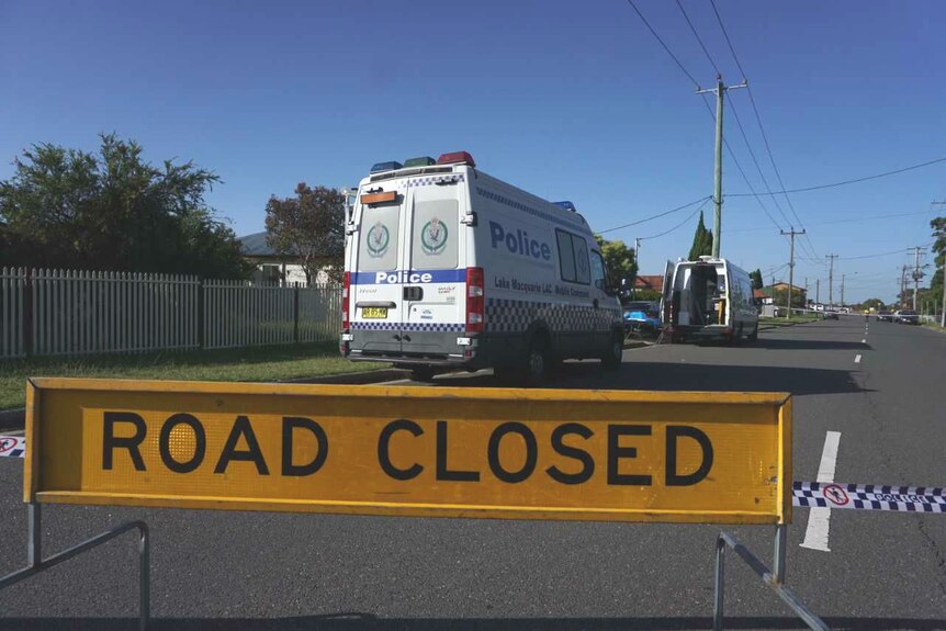 A road closed sign in front of a police van