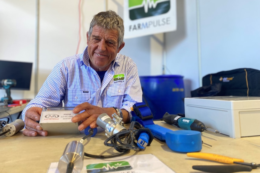 James sits on a crowded ag tech desk, with a big smile as he shows off one of his gadgets.