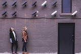 Two women look up at multiple CCTV cameras