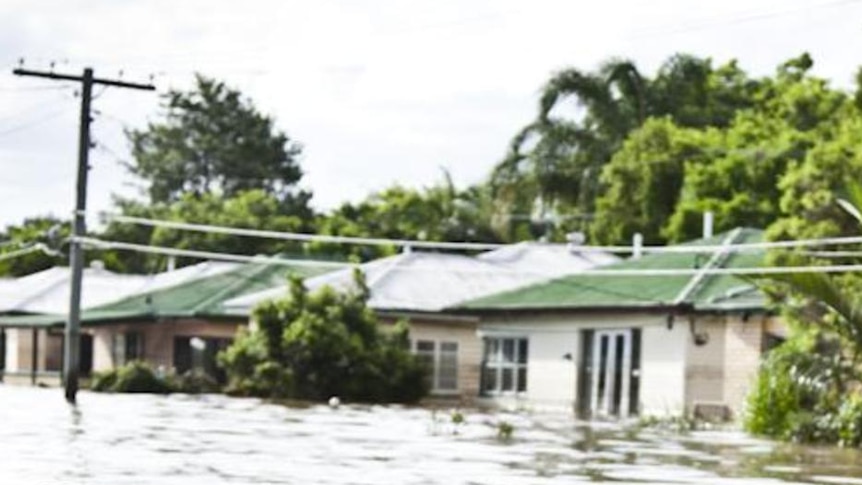 Floodwaters consume a road subject to flooding sign.