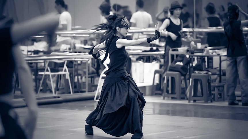 A black and white photo of Yang Liping dancing in a rehearsal room.