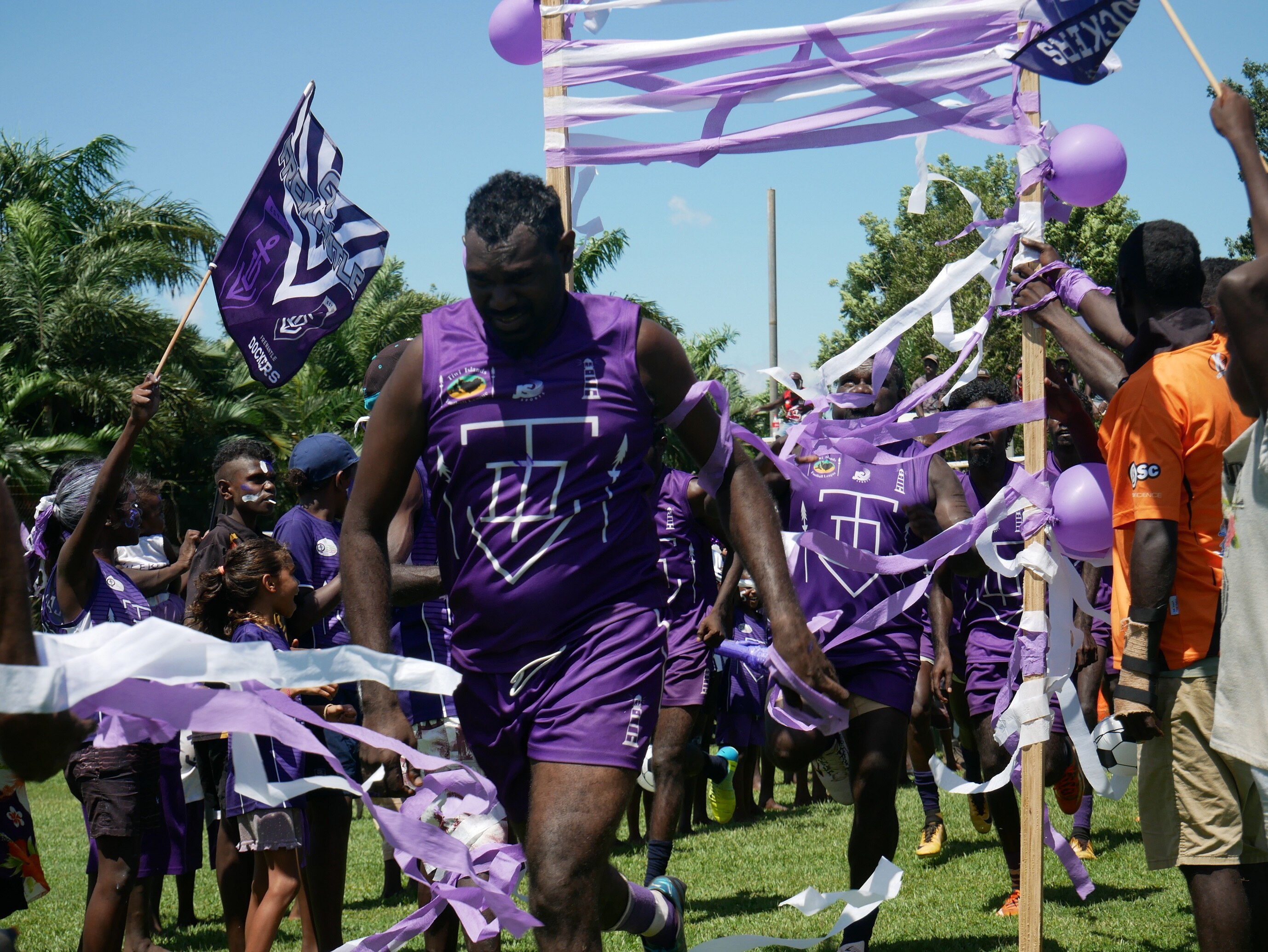Dockers players run through a banner onto the field for the football grand final.