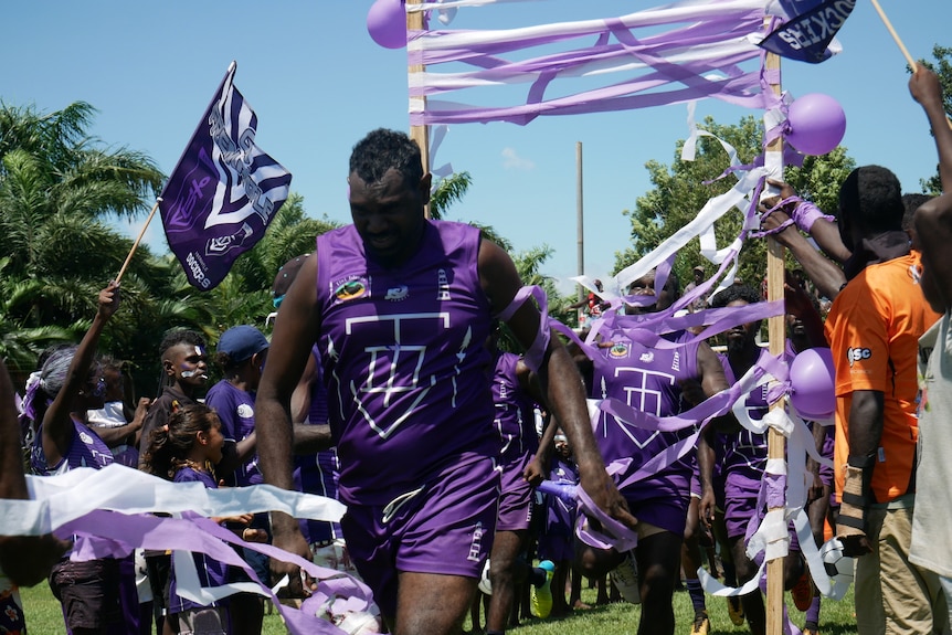 Dockers players run through a banner onto the field for the football grand final.