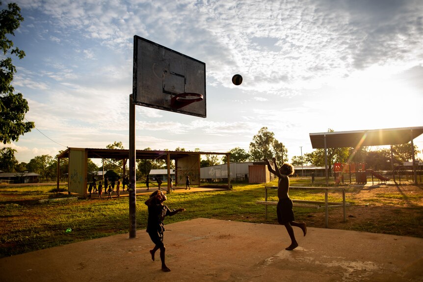 Two children play on a basketball court in Rockhole.