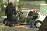 A member of the bomb squad examines an explosive device found in a car at Redbank Plaza shopping centre on April 2, 2018.
