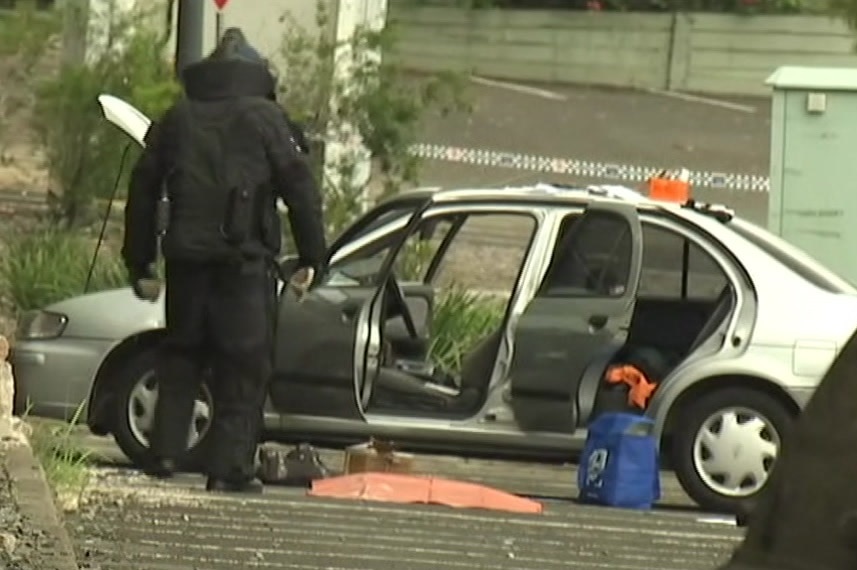 A member of the bomb squad examines an explosive device found in a car at Redbank Plaza shopping centre on April 2, 2018.