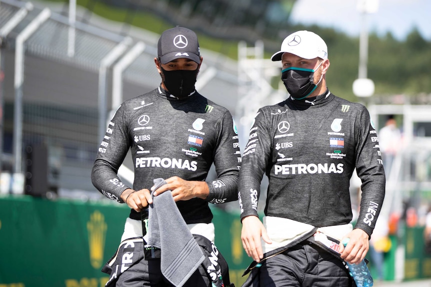 Valtteri Bottas and Lewis Hamilton walk next to each other, both wearing facemasks