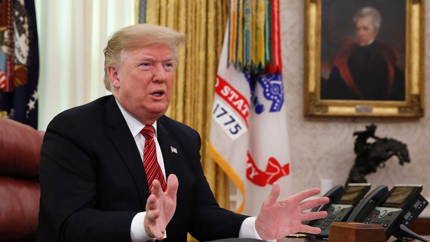 President Donald Trump siting at his desk in the Oval office