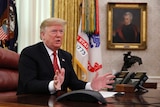 President Donald Trump siting at his desk in the Oval office
