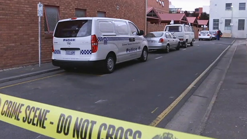 Police tape cordons off a crime scene on a lane behind some city units.