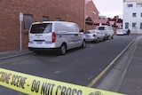 Police tape cordons off a crime scene on a lane behind some city units.