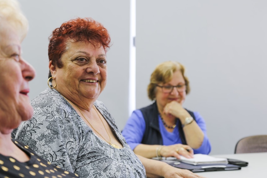 Mary Rose Borg smiles as she sits in a room with other senior women.