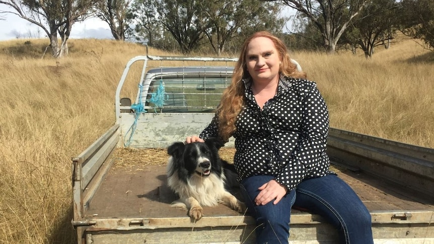 A young woman and her dog sitting in the back of a ute.