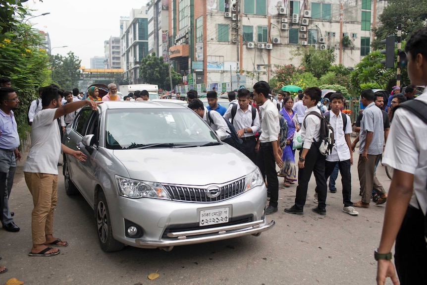 Students are seen stopping a  car during a protest.