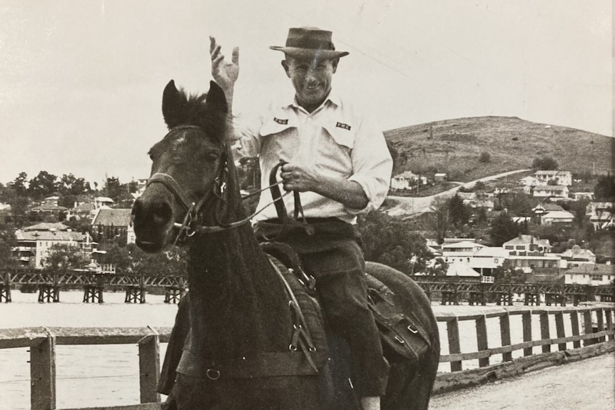 An old photo shows a man on a horse on a bridge.