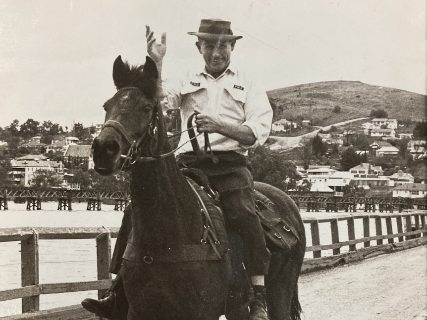 An old photo shows a man on a horse on a bridge.