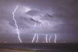 Forks of lightning spearing into rough seas at night.