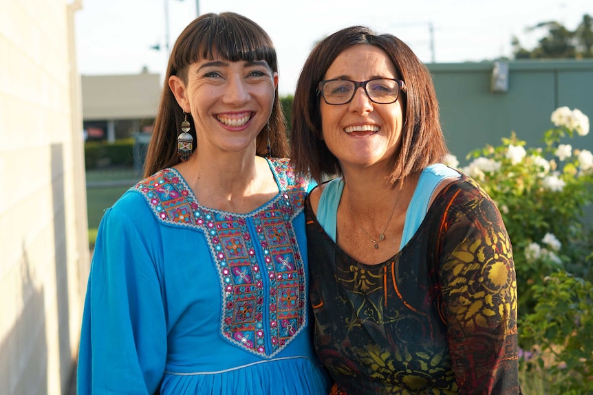 Two women standing next to each other smiling.