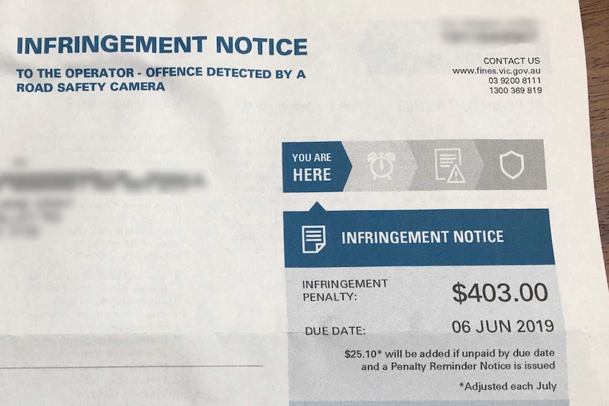 A traffic infringement notice for a red light camera with the name and details blurred out.