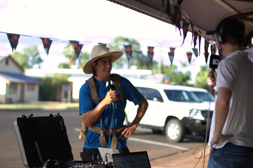 A man wearing an akubra speaking into an ABC branded microphone. 